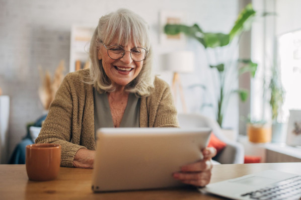 Eine Seniorin liest auf ihrem Tablet das AOK Magazin Osteoporose.