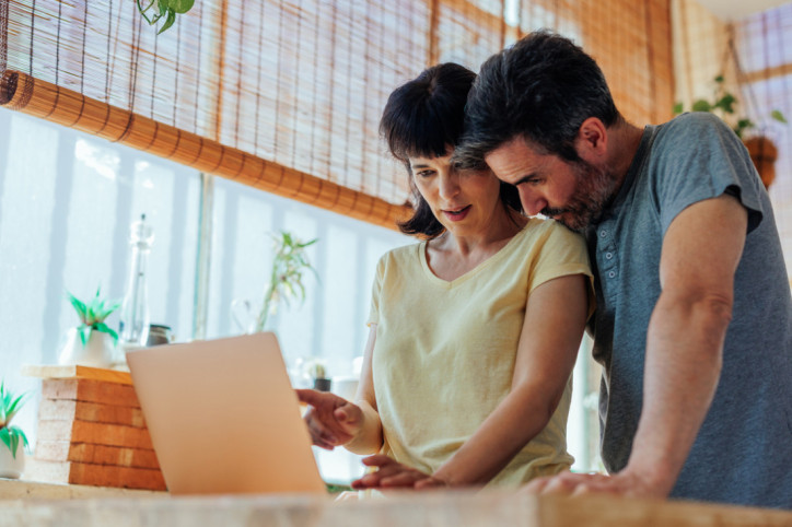 Ein Paar steht zusammen vor dem Laptop und prüft den Zusatzbeitrag der AOK Sachsen-Anhalt.