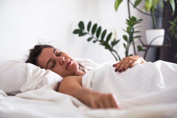 Eine etwa 30 jährige Frau liegt in einem Bett und schläft.