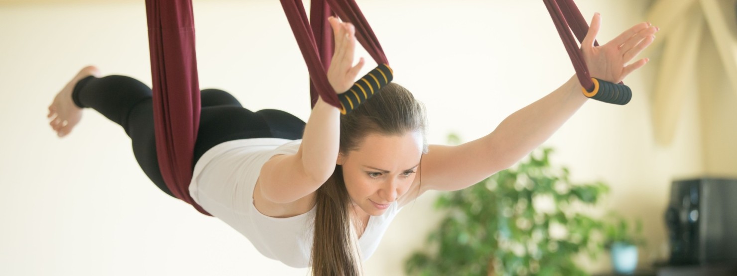 Junge Frau hängt in einem Yoga-Seil.