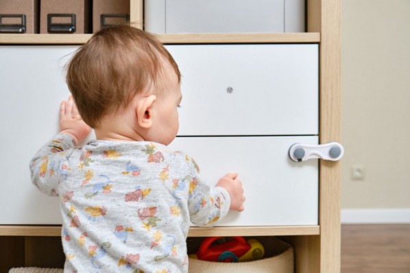 Ein Baby greift an einen Schrank an dem einer Sicherung dran montiert ist.