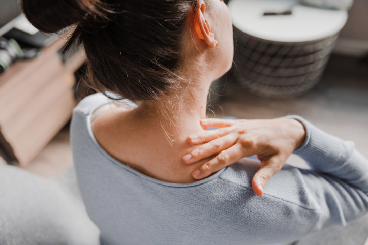 Eine Frau ertastet ihre muskuläre Dysbalance am Hals