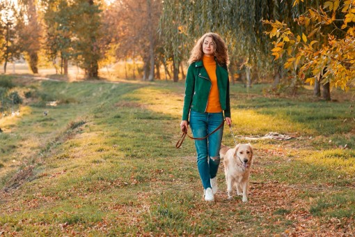 Eine etwa 55 jährige Frau geht mit ihrem Hund in der Natur spazieren.