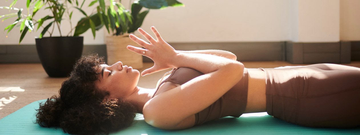 Eine Frau praktiziert Yoga Nidra auf einer Matte