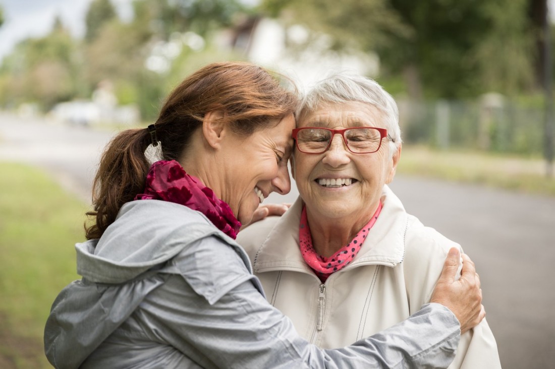 eine ca. 50-jährige Frau umarmt ihre Mutter. beide lächeln