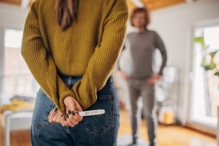 Frau teilt ihrem Partner das Ergebnis ihres Schwangerschaftstest mit.