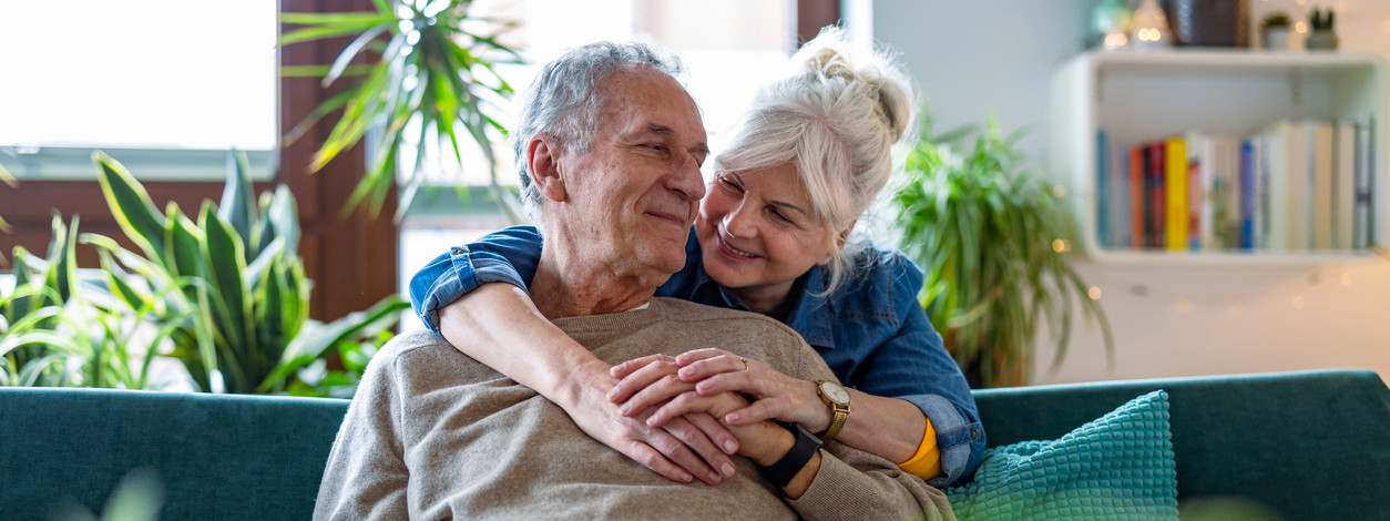 Porträt eines glücklichen Seniorenpaares, das zu Hause auf dem Sofa sitzt