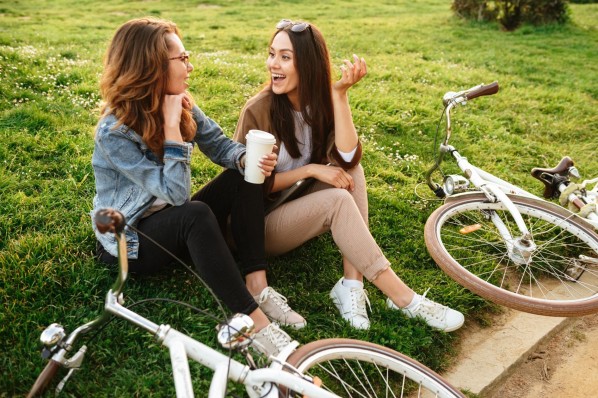 Zwei Frauen sitzen im Gras und unterhalten sich