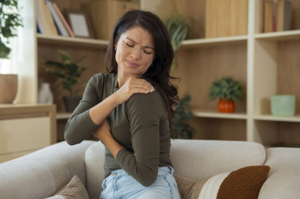 Eine Frau klagt über Schulterschmerzen aufgrund von Osteoporose