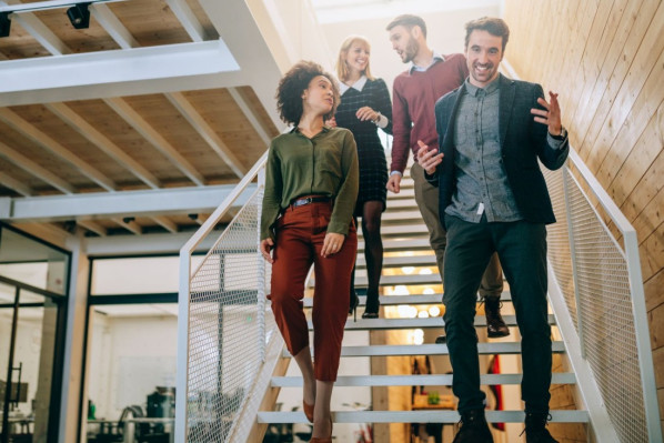 Kollegen laufen gemeinsam eine Treppe hinunter und unterhalten sich angeregt.