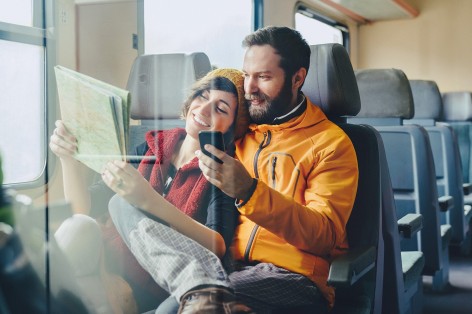 Frau und Mann mit Karte und Smartphone im Zug
