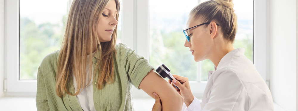 Eine Hautärztin führt ein Hautkrebsscreening bei einer Patientin durch