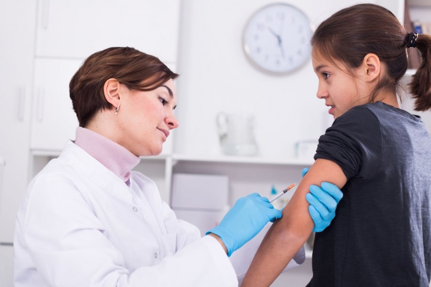 Ein etwa 6 jähriges Mädchen wird von einer Ärztin in den linken Arm geimpft.