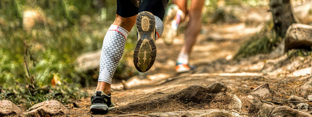 Zwei Personen laufen beim Trailrunning durch den Wald