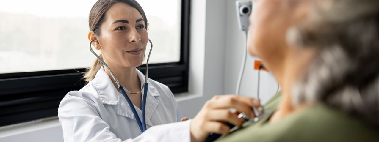 Ärztin untersucht ältere Patientin mit einem Stetoskop.
