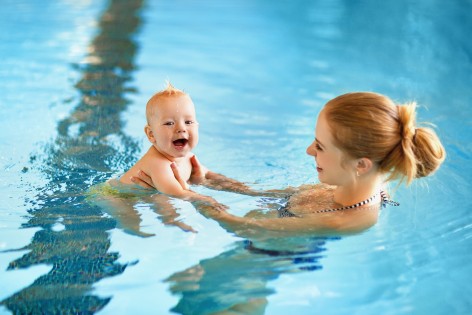 Mutter mit Baby im Wasser eines Schwimmbades.