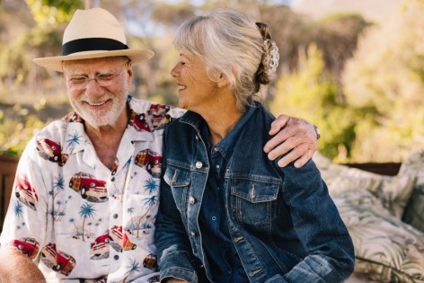 Happy senior couple smiling cheerfully while relaxing at a spa resort. Romantic elderly couple enjoying their summer vacation together. Grey-haired couple enjoying life after retirement.