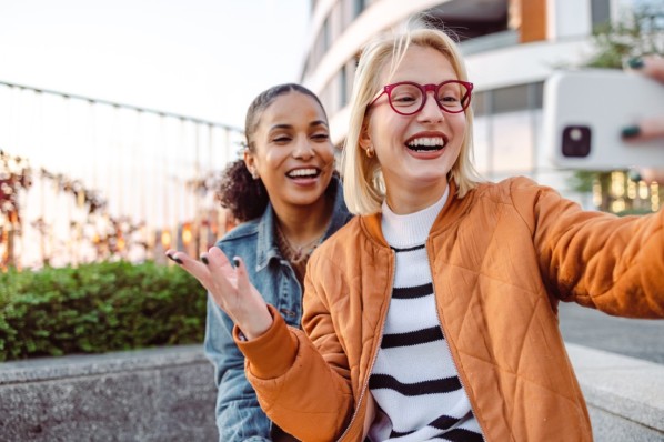 Two young women smiling and taking selfie in the city