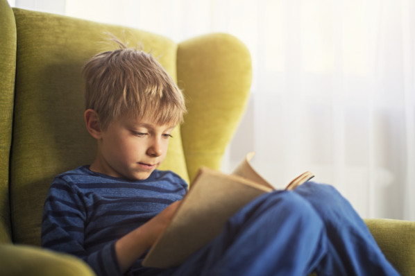 ca 7 jähriges Mädchen mit Locken liest in einem gelben Buch