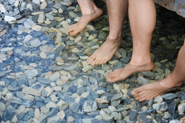 Zwei paar nackte Füße werden in flachem Wasser gekühlt.