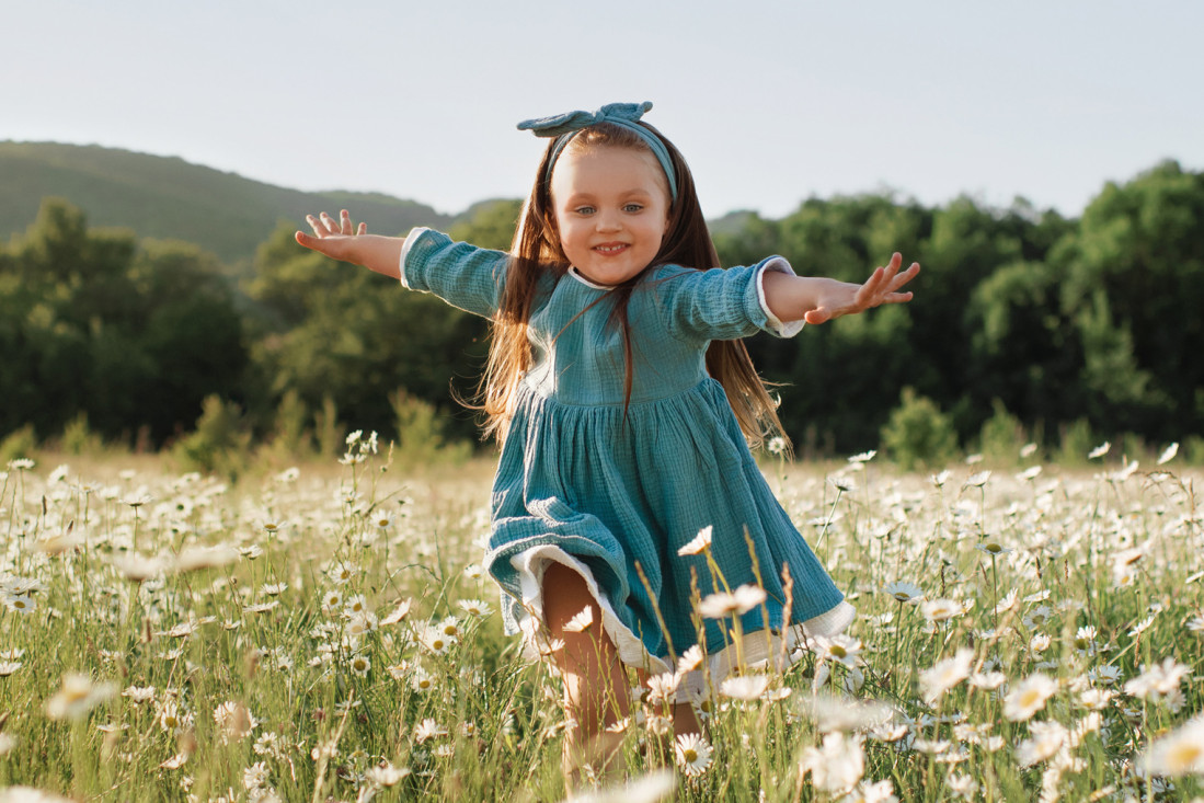 Glückliches Kind spielt auf einer sonnigen Wiese. - AOK Sachsen-Anhalt bietet umfassenden Gesundheitsschutz für Familien.