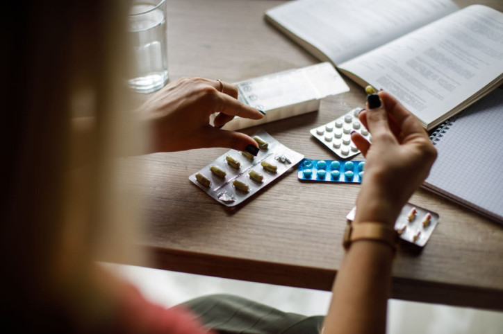 Eine Frau betrachtet verschiedene Antibiotika, die vor ihr auf dem Tisch liegen