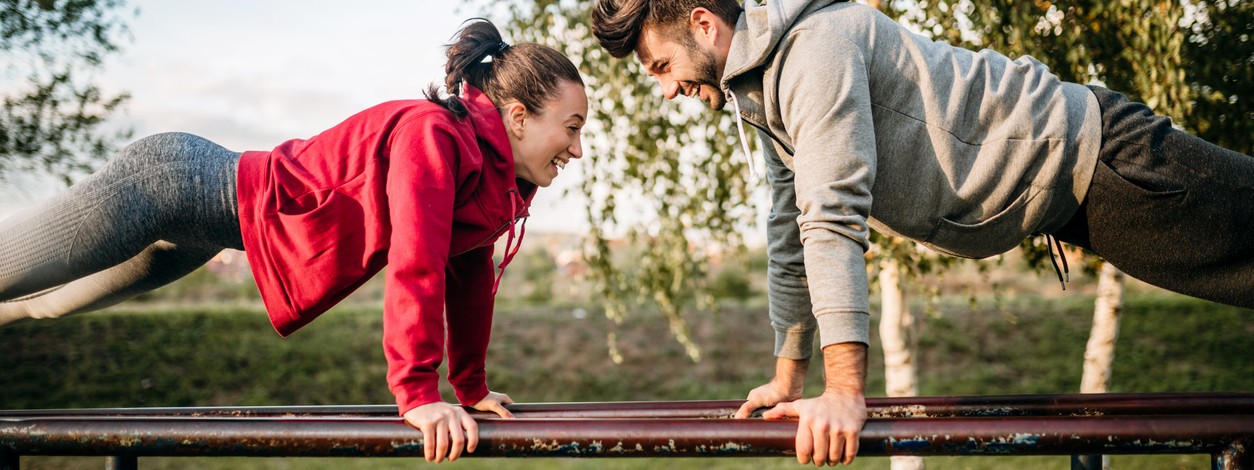 Ein junges Paar trainiert im Outdoor-Park auf einem Barren.