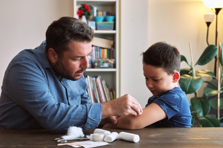 Ein Vater wendet das Wissen aus einem Kinder-Erste-Kurs bei seinem Sohn an