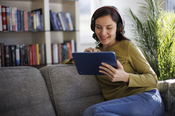 Frau Anfang 30 mit Kopfhörern konsumiert digitale meiden auf dem Tablet