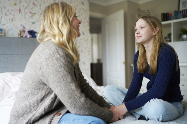 Reife Mutter, Die Mit Teenager-Tochter Zu Hause Auf Dem Bett Sitzt