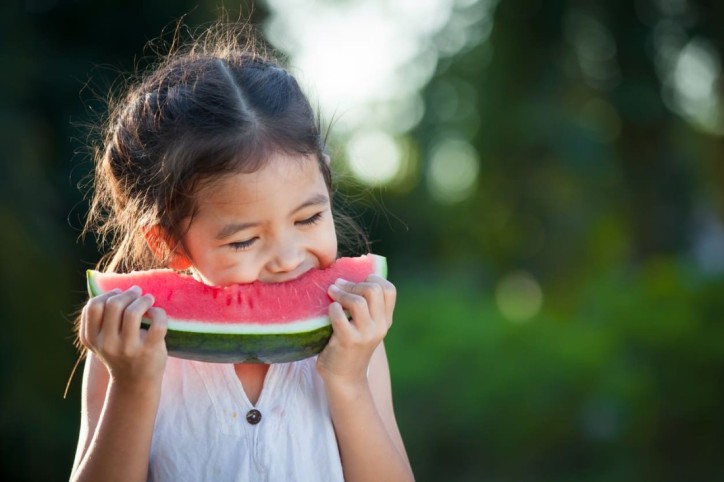 Ein Kind isst ein Stück Wassermelone gegen Dehydration
