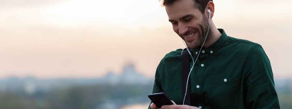 Ein etwas 35-jähriger Mann hört den Gesundheitswissen kompakt Podcast der AOK Sachsen-Anhalt auf seinem Handy.