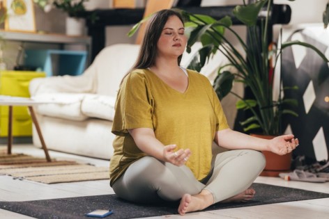 Eine Frau meditiert auf ihrer Yogamatte.