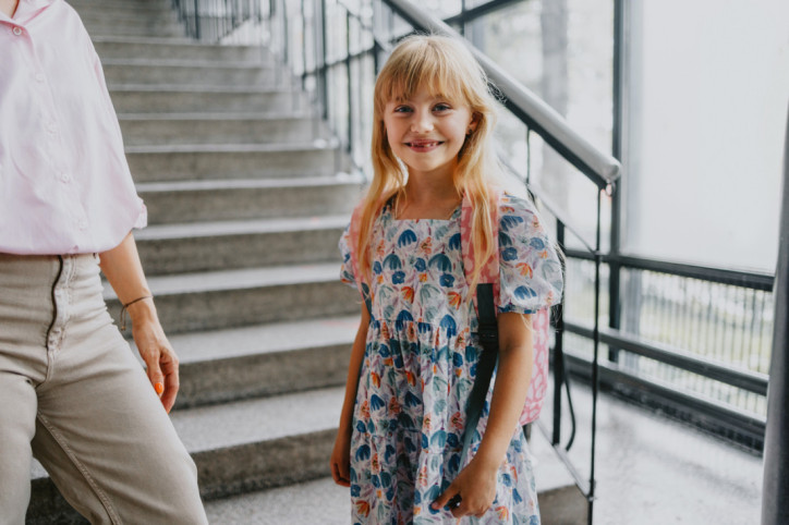 Mädchen mit Schulranzen vor Treppe im Schulgebäude