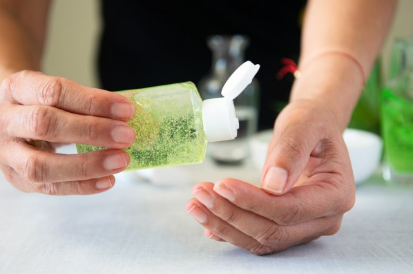 Eine Frau gibt Aloe-Vera-Gel aus einer Flasche auf ihre Hand.