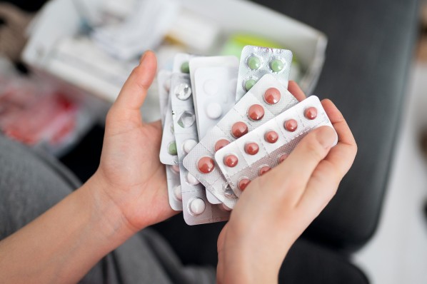Hände halten eine Sammlung verschiedener verpackter Tabletten.