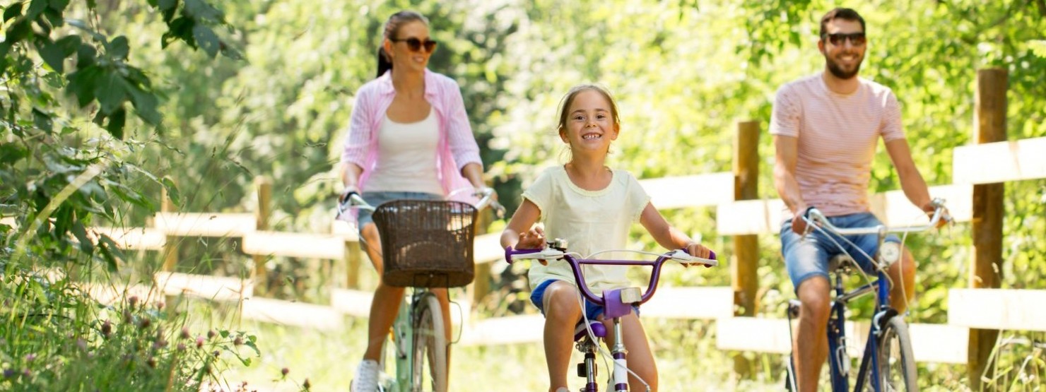 Eine junge Familie fährt mit ihren Fahrrädern durch die Natur.