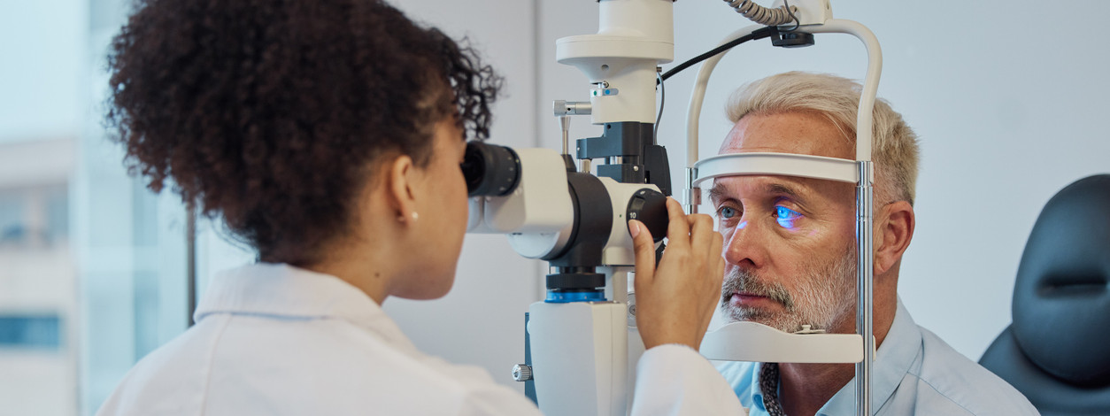 Ein männlicher Patient wird von einer Augenärztin am Auge untersucht.