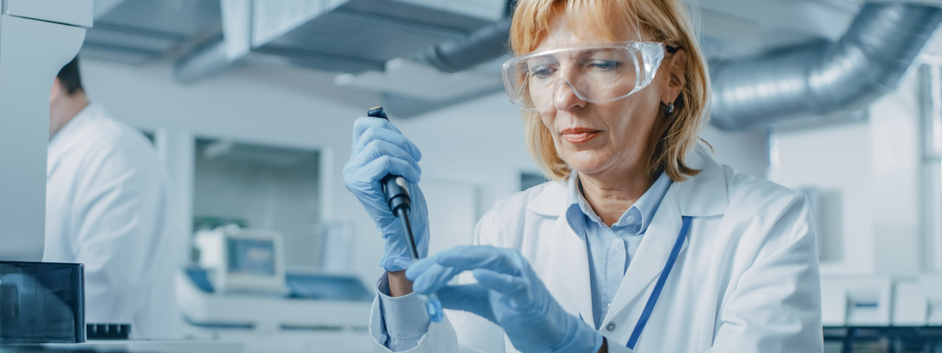 Eine Laborantin füllt mit Hilfe eine Mikropipette eine Flüssigkeit in ein Teströhrchen ab.