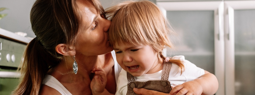 Eine Mutter tröstet ihr fremdelndes Kleinkind.