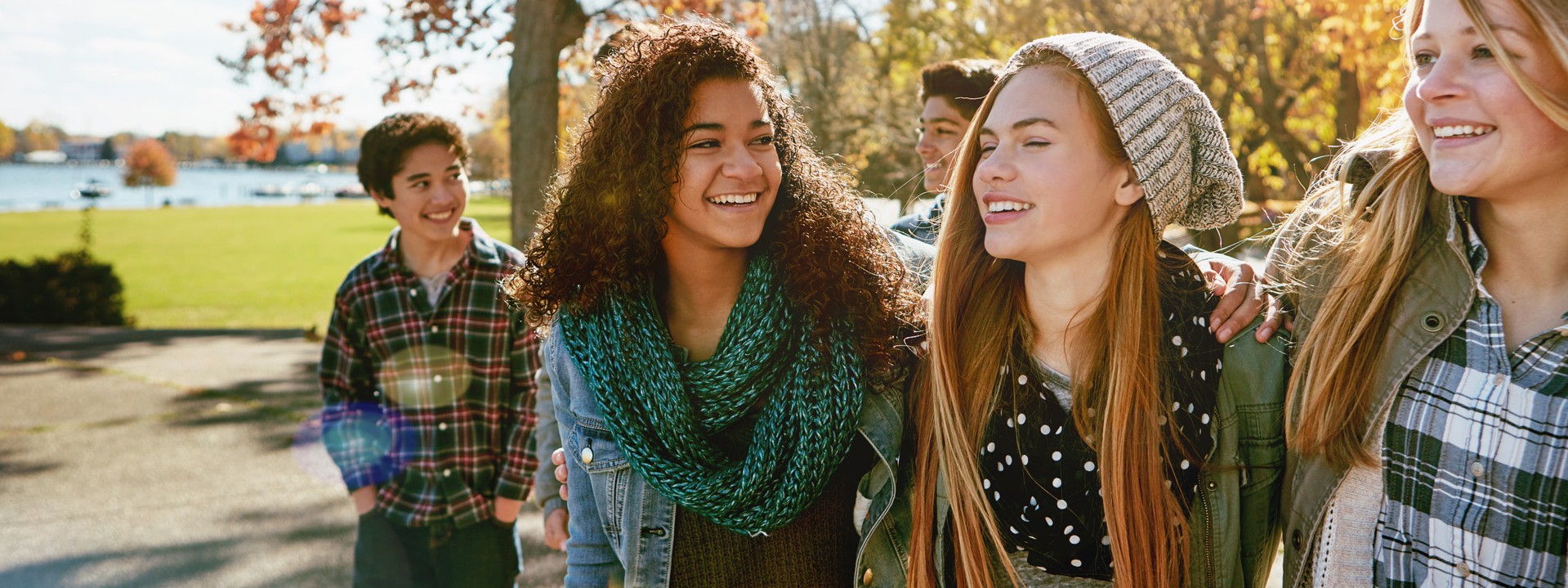 Eine Gruppe von 5 Teenagern fröhlich lächelnd in der Herbstsonne.