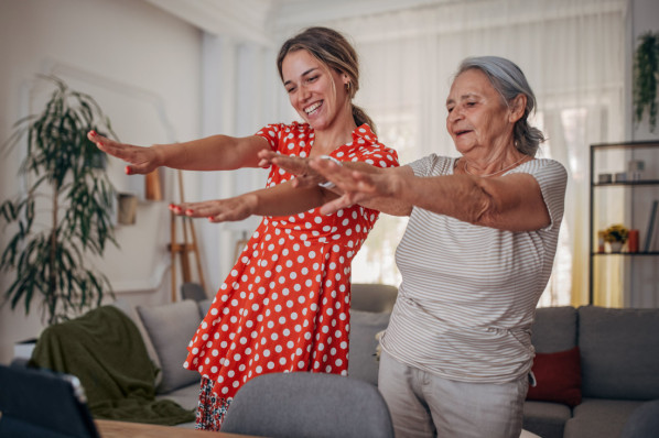 Junge und ältere Frau machen gemeinsam Fitnessübungen vor einem Tablet. – AOK Sachsen-Anhalt begleitet mit starken Leistungen.