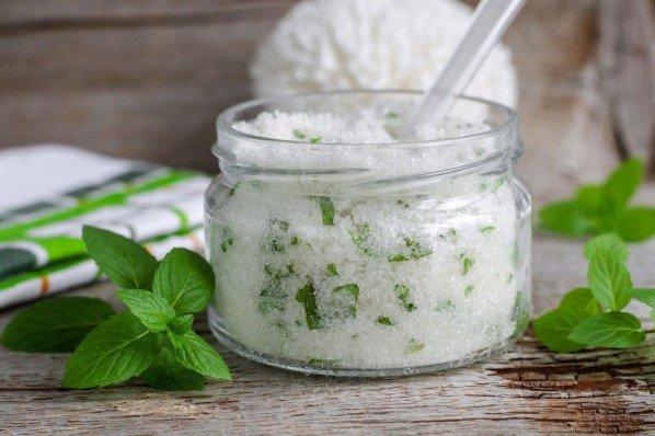 Refreshing homemade sugar scrub with vegetable oil, chopped mint leaves and essential mint oil