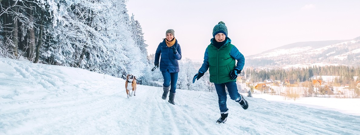 Mutter und sohn laufen durch verschneite Landschaft