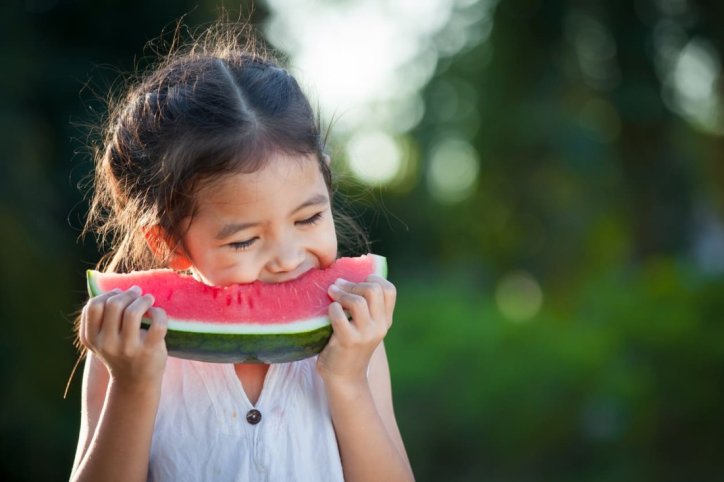 Ein Kind isst ein Stück Wassermelone gegen Dehydration