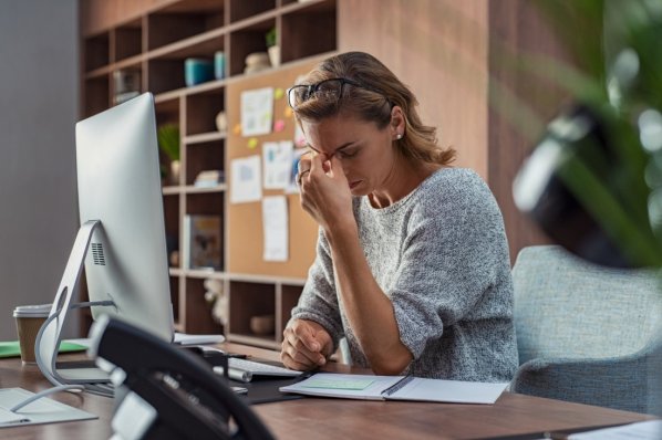 Eine Frau sitzt erschöpft an ihrem Schreibtisch im Büro.