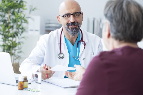 Arzt übergibt einem Patienten ein Rezept