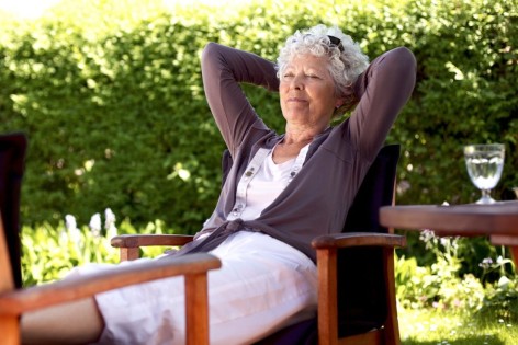 Senior woman sitting on a chair and taking a nap in backyard. Elder woman sleeping in backyard garden