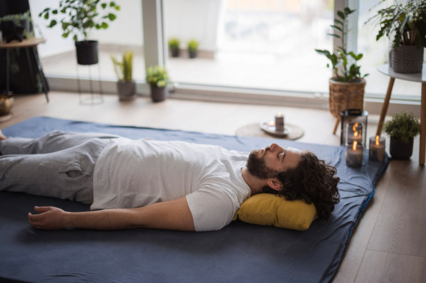 Ein Mann beim entspannten Yoga Nidra zu Hause