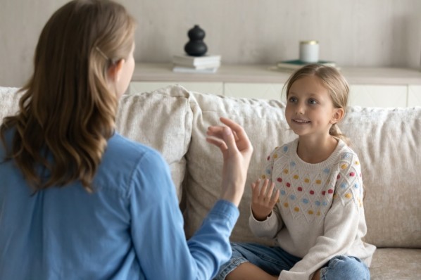 Eine Sprachtherapeutin übt mit einem kleinen Mädchen Sprechübungen und Laute.